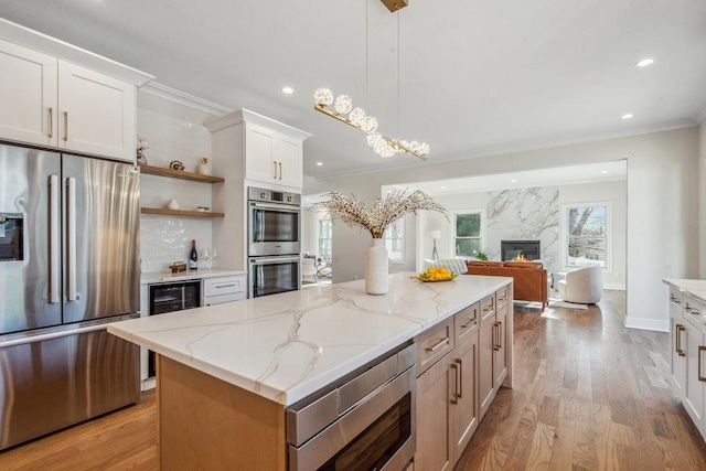 kitchen featuring white cabinetry, decorative light fixtures, light stone countertops, and appliances with stainless steel finishes