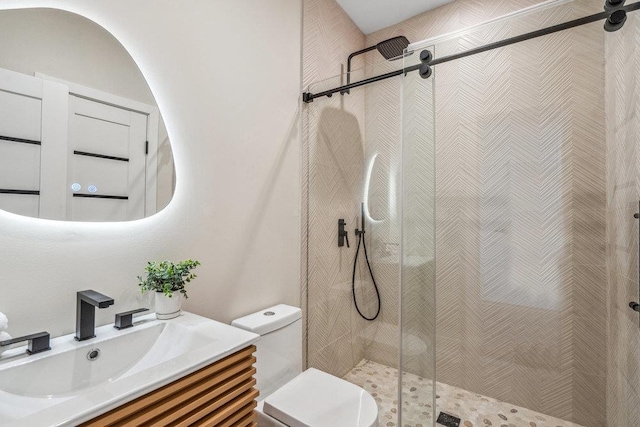 bathroom featuring vanity, a shower with shower door, and toilet