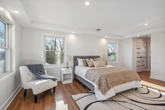 bedroom featuring a tray ceiling and dark hardwood / wood-style flooring