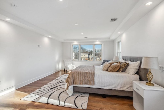 bedroom with a tray ceiling and wood-type flooring