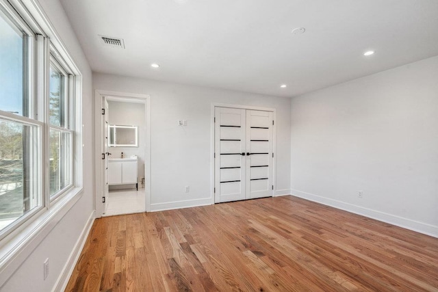 unfurnished bedroom with connected bathroom, light hardwood / wood-style flooring, and a closet