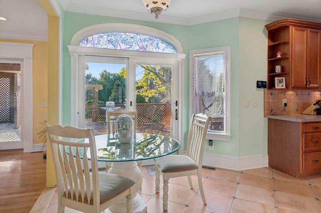 dining room featuring light tile patterned flooring, crown molding, visible vents, and baseboards