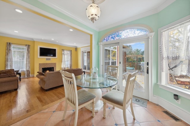 dining space featuring baseboards, visible vents, ornamental molding, and a tile fireplace