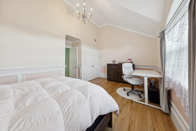 bedroom featuring lofted ceiling, crown molding, visible vents, and wood finished floors