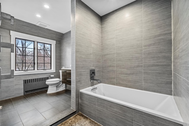 full bath featuring tile patterned flooring, toilet, a relaxing tiled tub, tile walls, and radiator heating unit