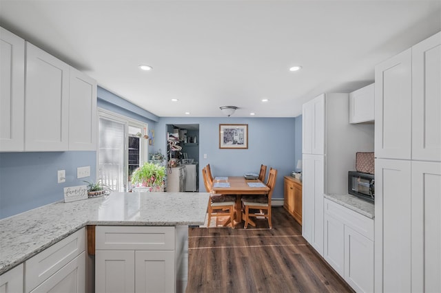 kitchen featuring dark hardwood / wood-style floors, white cabinetry, kitchen peninsula, washing machine and dryer, and light stone countertops