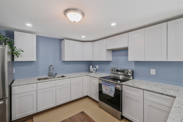 kitchen with white cabinetry, appliances with stainless steel finishes, light stone countertops, and sink