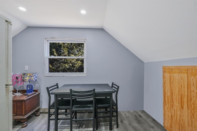 dining area featuring hardwood / wood-style flooring and vaulted ceiling