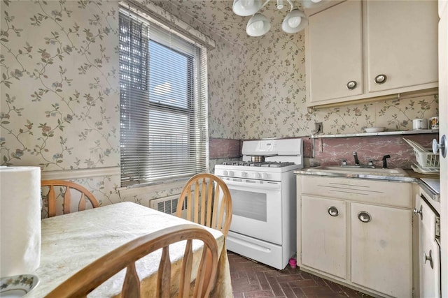 kitchen featuring cream cabinets, sink, and gas range gas stove