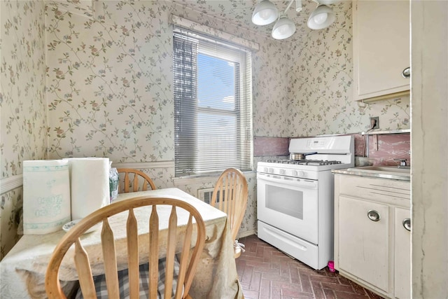 kitchen featuring sink, white range with gas stovetop, and a notable chandelier