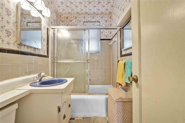 bathroom with vanity, enclosed tub / shower combo, and tile walls