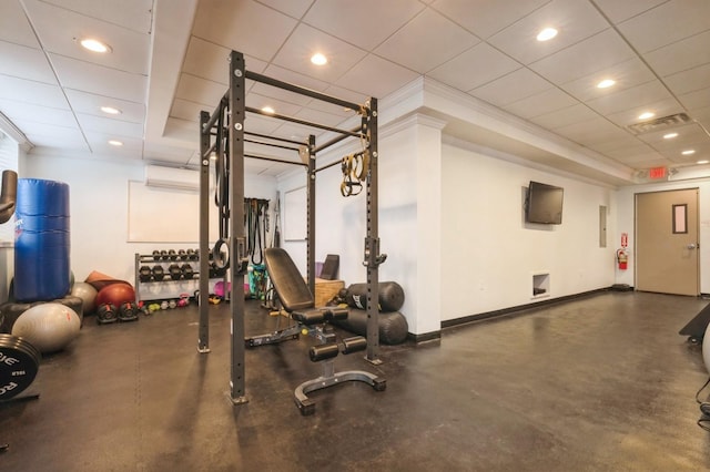 gym with a drop ceiling, crown molding, and a wall unit AC