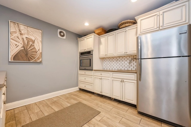 kitchen with tasteful backsplash, sink, stainless steel appliances, and cream cabinetry