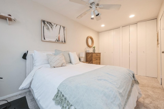 carpeted bedroom with ceiling fan and two closets