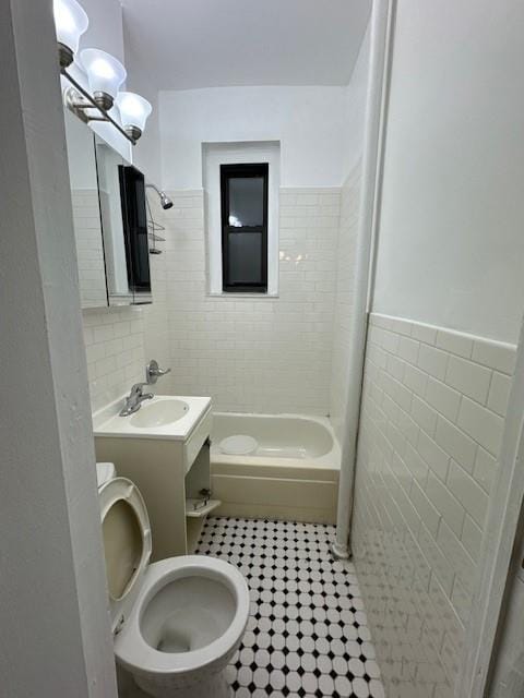 full bathroom with tile walls, tiled shower / bath combo, vanity, toilet, and tile patterned floors