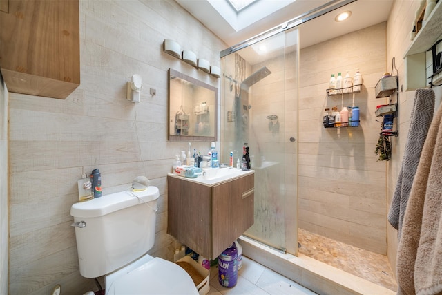 bathroom with tile walls, vanity, a skylight, an enclosed shower, and toilet