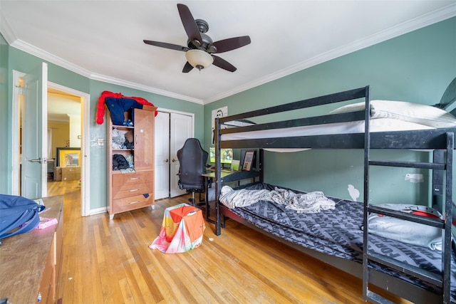 bedroom with ceiling fan, ornamental molding, wood-type flooring, and a closet