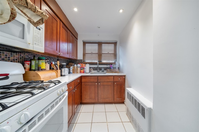 kitchen with heating unit, sink, backsplash, white appliances, and light tile patterned floors