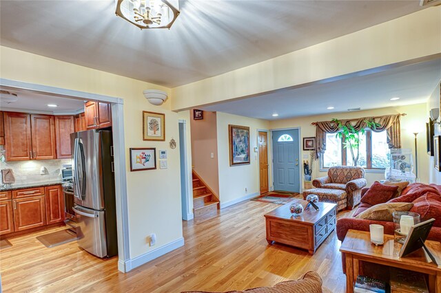 living room featuring baseboards, light wood finished floors, and stairway