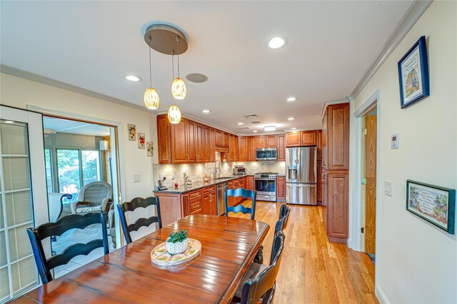 dining area with crown molding, recessed lighting, and light wood-type flooring
