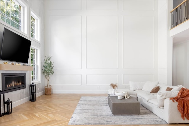 living room with a wealth of natural light, a tile fireplace, and light parquet floors