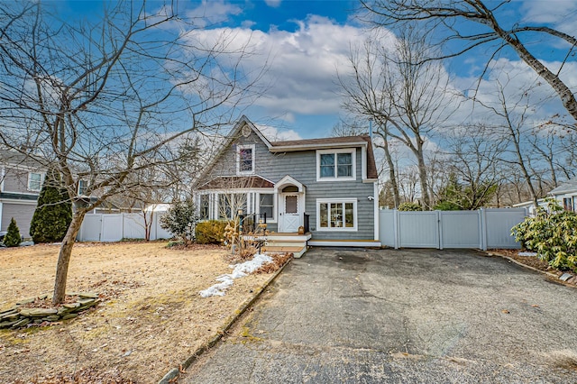 shingle-style home featuring aphalt driveway, fence, and a gate