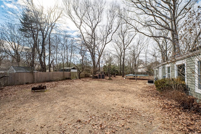 view of yard featuring a trampoline and fence