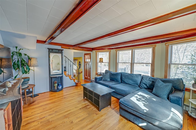 living room with light wood-type flooring, beamed ceiling, stairway, and a baseboard radiator