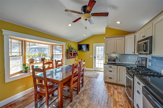 kitchen featuring lofted ceiling, stainless steel appliances, plenty of natural light, tasteful backsplash, and dark countertops