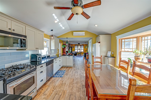 kitchen with dark countertops, a peninsula, vaulted ceiling, stainless steel appliances, and a sink