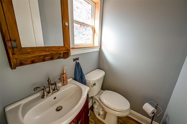 half bath with vanity, toilet, and baseboards