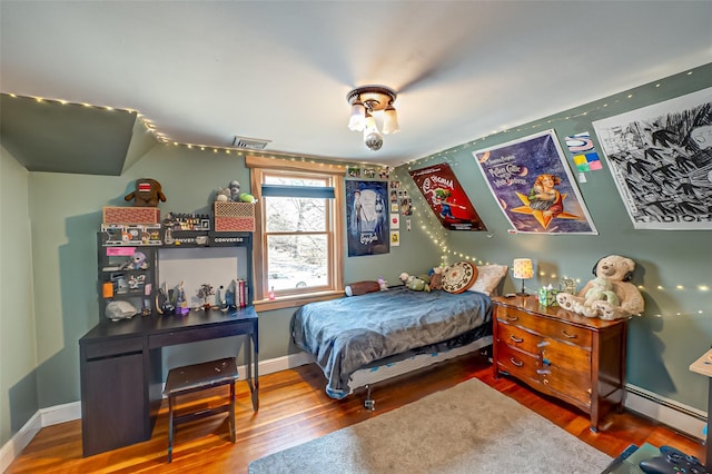 bedroom with a baseboard radiator, visible vents, baseboards, and wood finished floors