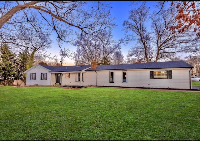 back house at dusk featuring a yard