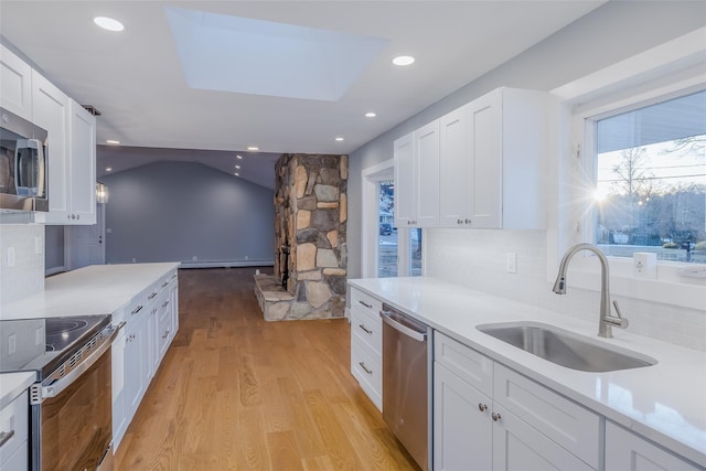 kitchen featuring sink, white cabinets, decorative backsplash, stainless steel appliances, and light wood-type flooring