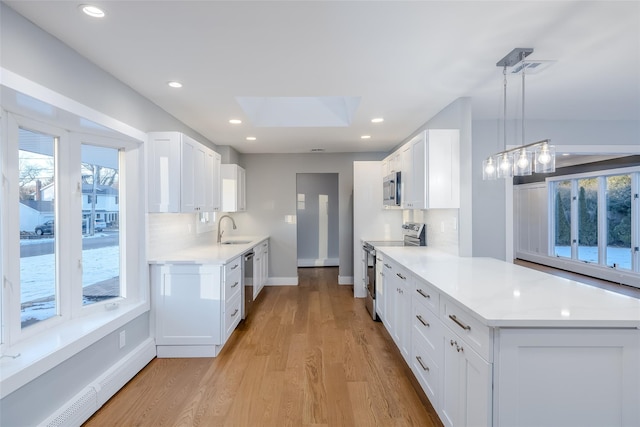 kitchen featuring white cabinetry, tasteful backsplash, baseboard heating, pendant lighting, and stainless steel appliances