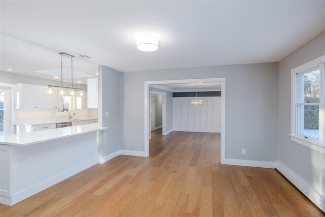 kitchen with hanging light fixtures, a baseboard heating unit, white cabinets, and kitchen peninsula