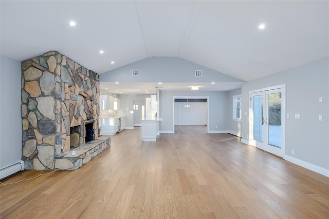 unfurnished living room with light hardwood / wood-style flooring, a stone fireplace, and vaulted ceiling