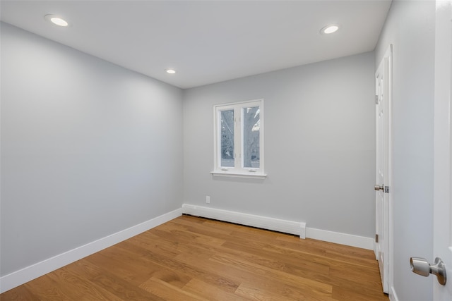 spare room with baseboard heating and light hardwood / wood-style flooring