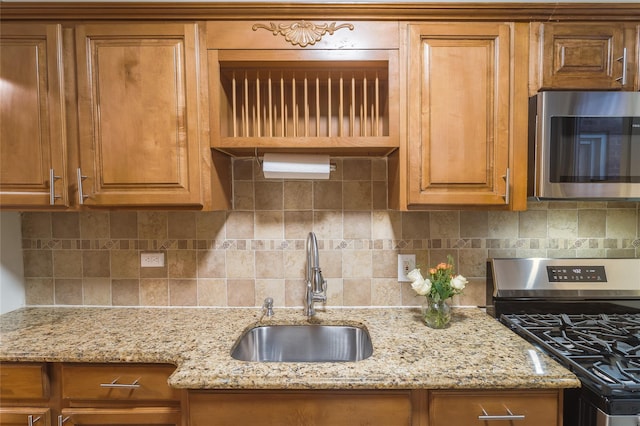 kitchen featuring tasteful backsplash, appliances with stainless steel finishes, sink, and light stone counters