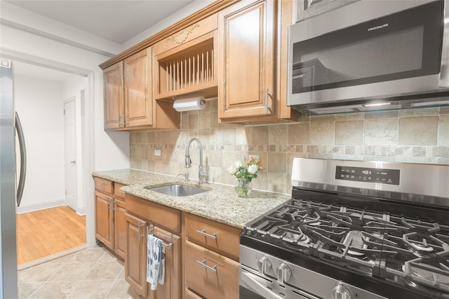 kitchen featuring sink, backsplash, light tile patterned floors, light stone counters, and stainless steel appliances