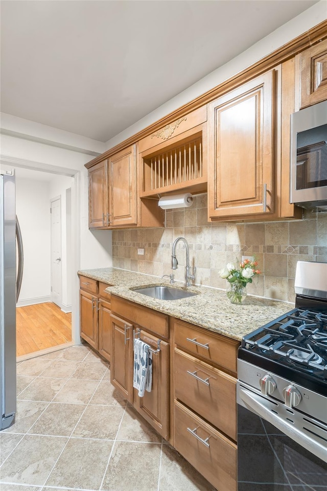 kitchen featuring sink, backsplash, stainless steel appliances, and light stone countertops