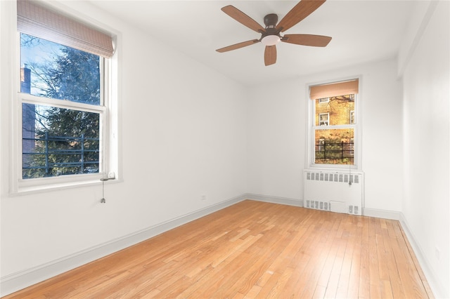 spare room with ceiling fan, radiator heating unit, and wood-type flooring