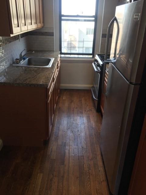 kitchen with sink, dark wood-type flooring, appliances with stainless steel finishes, tasteful backsplash, and light stone countertops