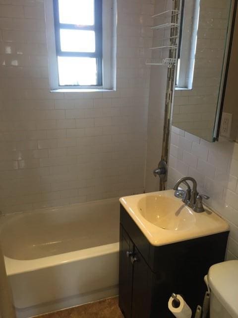 full bathroom featuring tile walls, vanity, tasteful backsplash, toilet, and tiled shower / bath