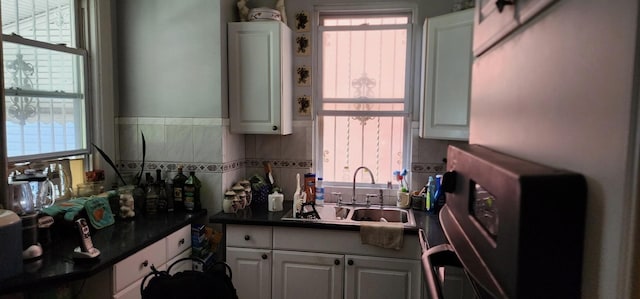 kitchen with dark countertops, a sink, and white cabinetry