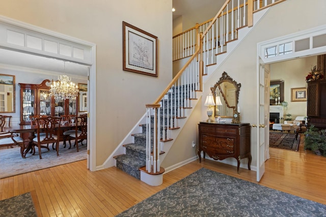 stairs with an inviting chandelier, hardwood / wood-style flooring, and a high ceiling