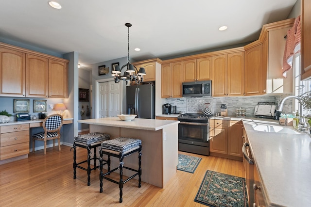 kitchen featuring sink, a center island, built in desk, hanging light fixtures, and stainless steel appliances