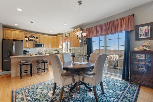 dining area with a notable chandelier and light hardwood / wood-style floors