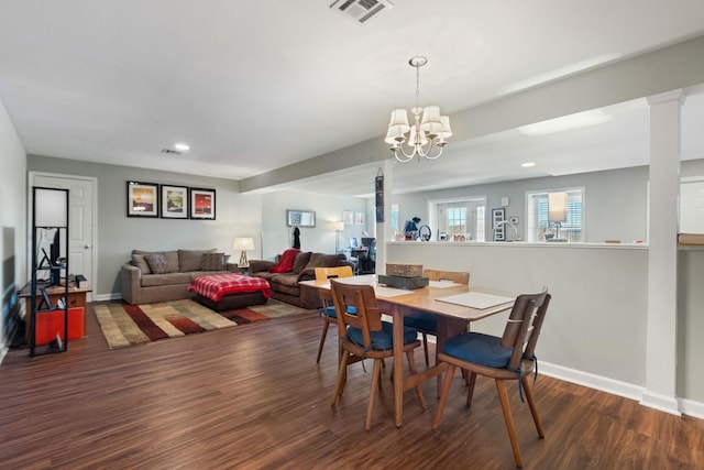 dining space with dark hardwood / wood-style flooring, a chandelier, and ornate columns