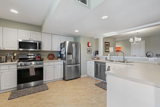 kitchen featuring pendant lighting, sink, appliances with stainless steel finishes, white cabinets, and kitchen peninsula